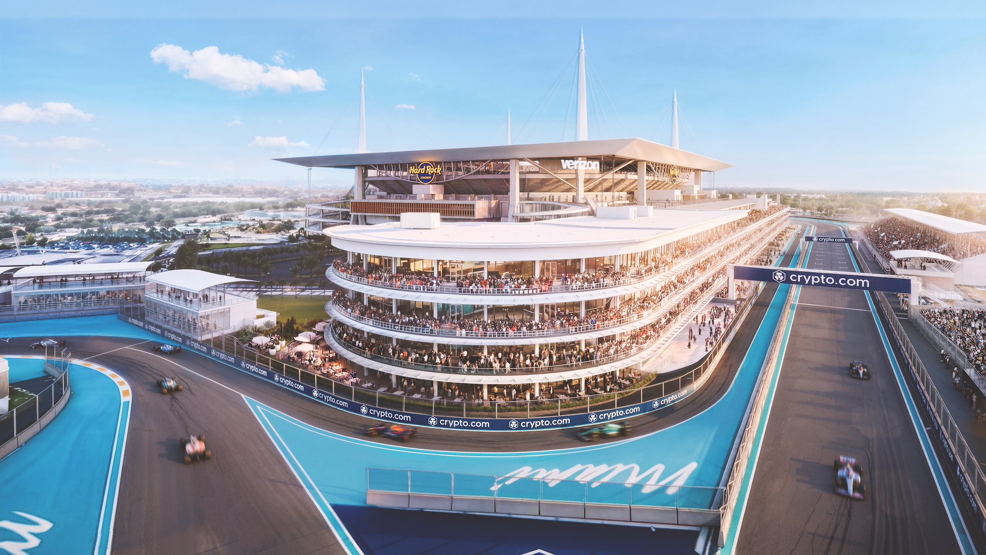 Aerial view of Formula 1 cars racing around the Miami International Autodrome, showcasing Hard Rock Stadium, packed grandstands, blue run‑off areas, and crypto.com-branded track bridges.