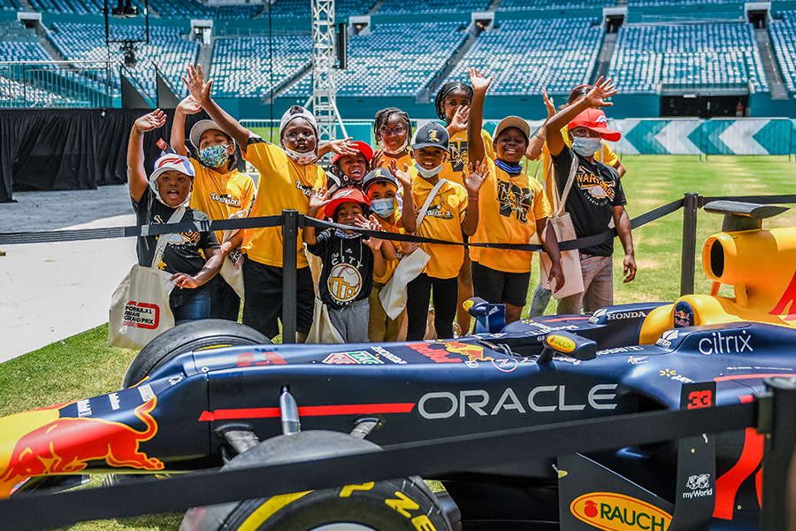 Image for a press release - kids pose with a Formula 1 car at the Formula 1 Miami Grand Prix Watch Party