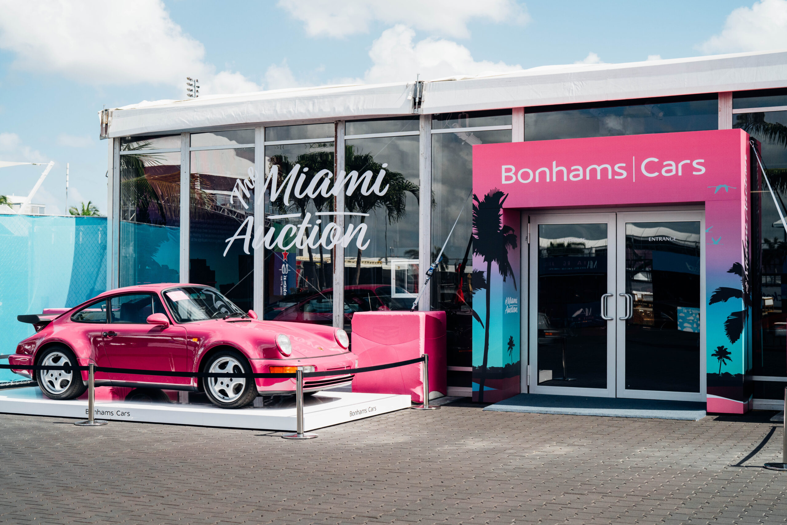 Photo of a classic porshe in bright magenta color being displayed in front of an activation