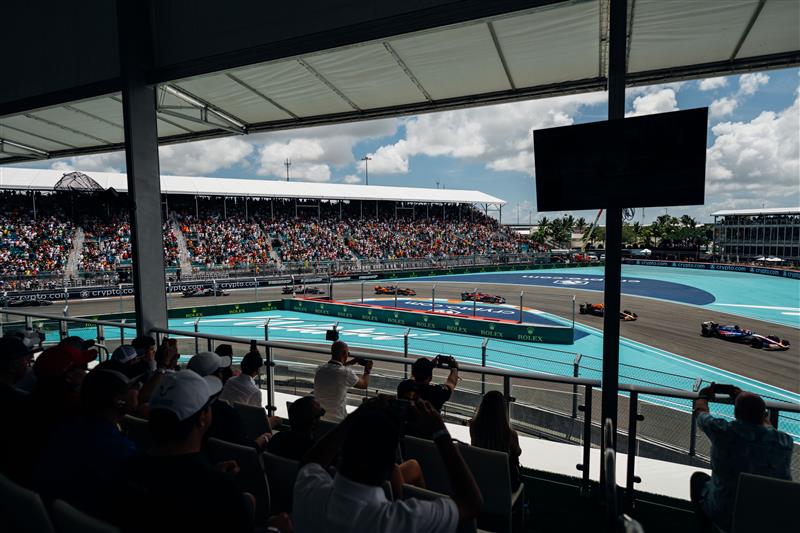 People watching the race with privileged view of the first turn while cars zoom by