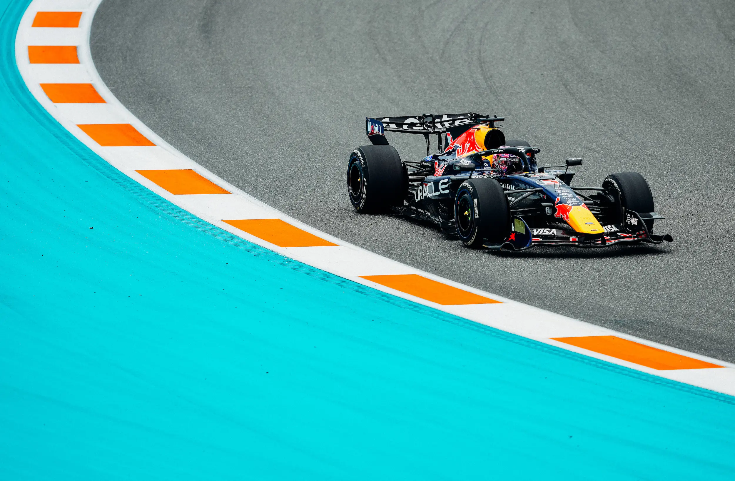 260503_F1MGP_Getty2274324785 High-angle view of a Red Bull Formula 1 car navigating a sweeping corner bordered by Miami Grand Prix turquoise runoff areas and orange-and-white curbing.