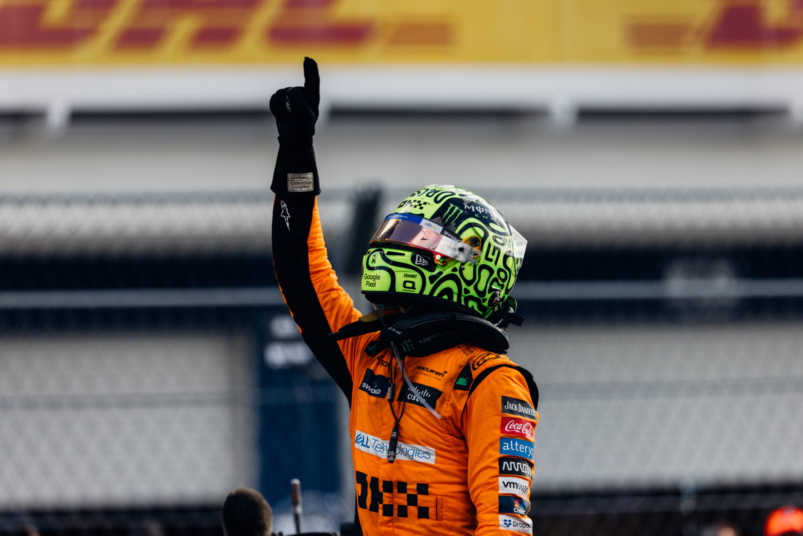 A McLaren driver holds up the number one with his hand