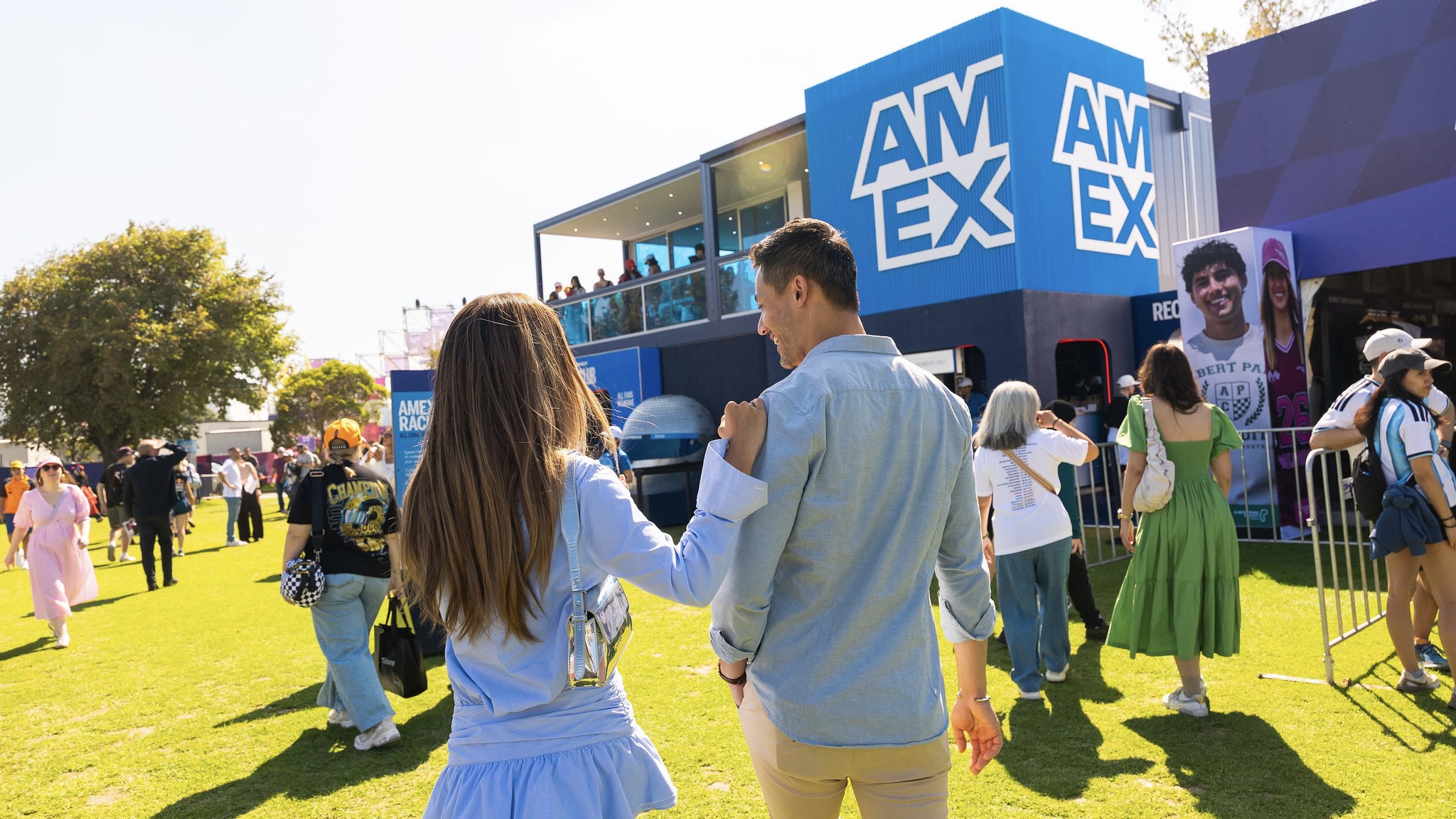 F1 Journey image Picture of a man and woman seen from behind smiling and walking towards the Amex activation
