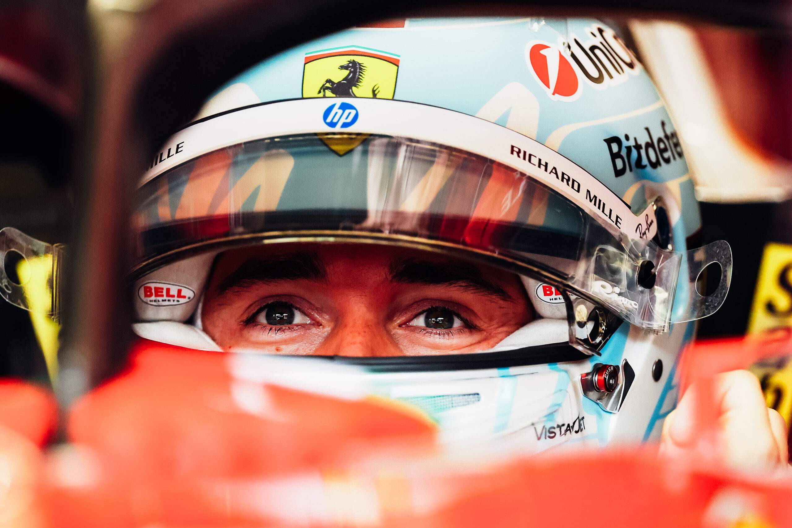 Close up of Charles Leclerc face covered with his Ferrari helmet as he prepares to take off
