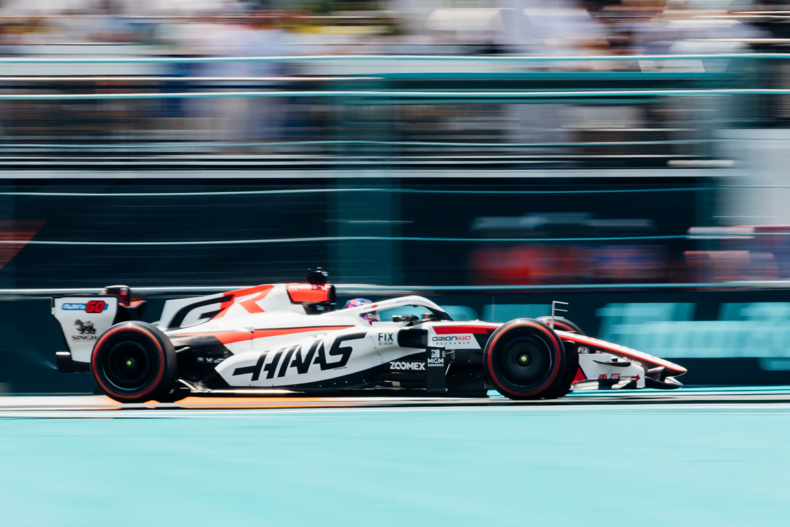 260501_F1MGP_RI7562 Side-profile panning shot of a Haas Formula 1 car racing through the Miami Grand Prix circuit, with the background blurred to emphasize speed and motion.