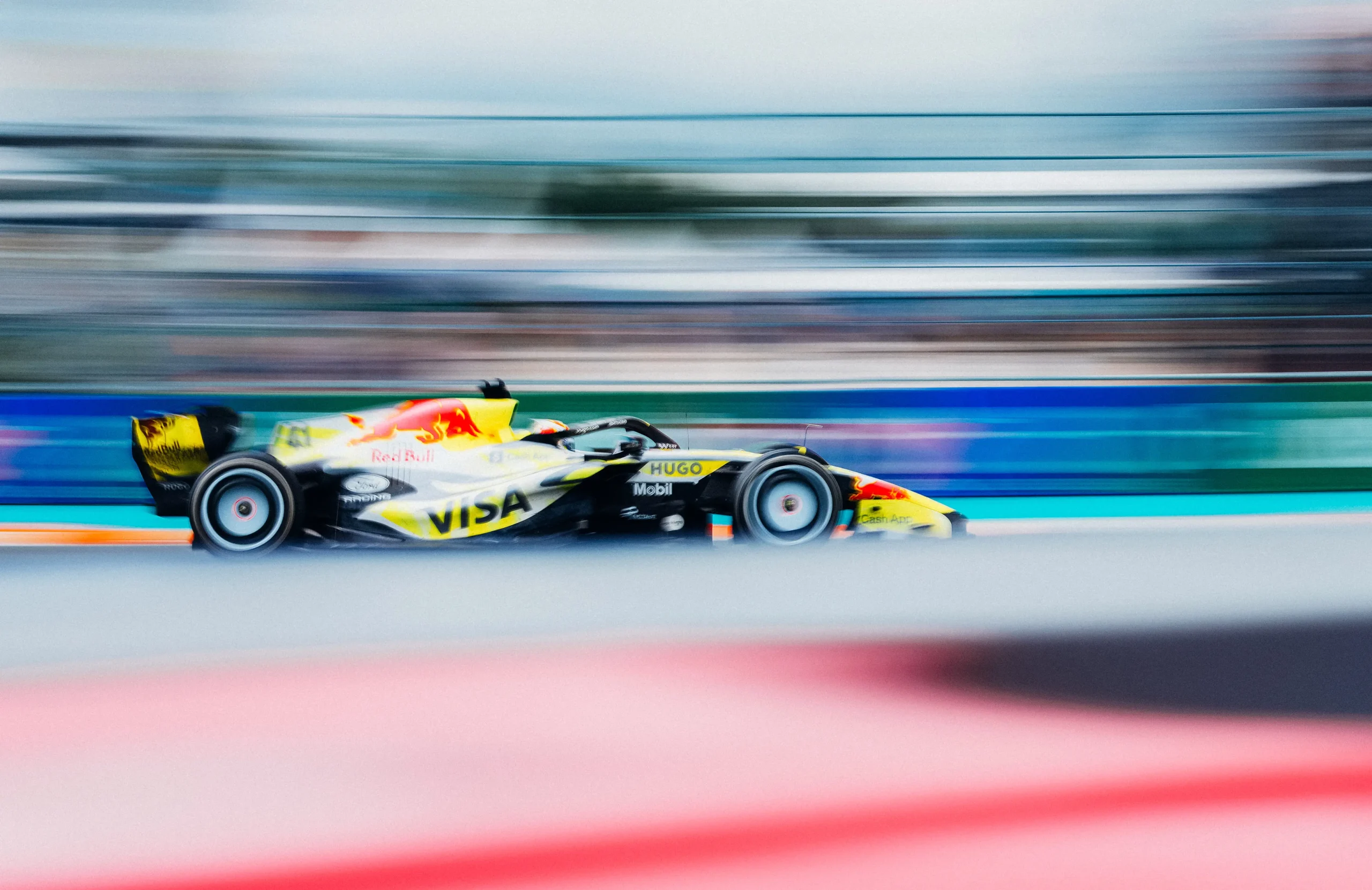 260503_F1MGP_Getty2274324763 (1) Side-profile panning shot of a Visa Cash App Racing Bulls Formula 1 car speeding through the Miami Grand Prix circuit, with the track and grandstands blurred to emphasize motion.