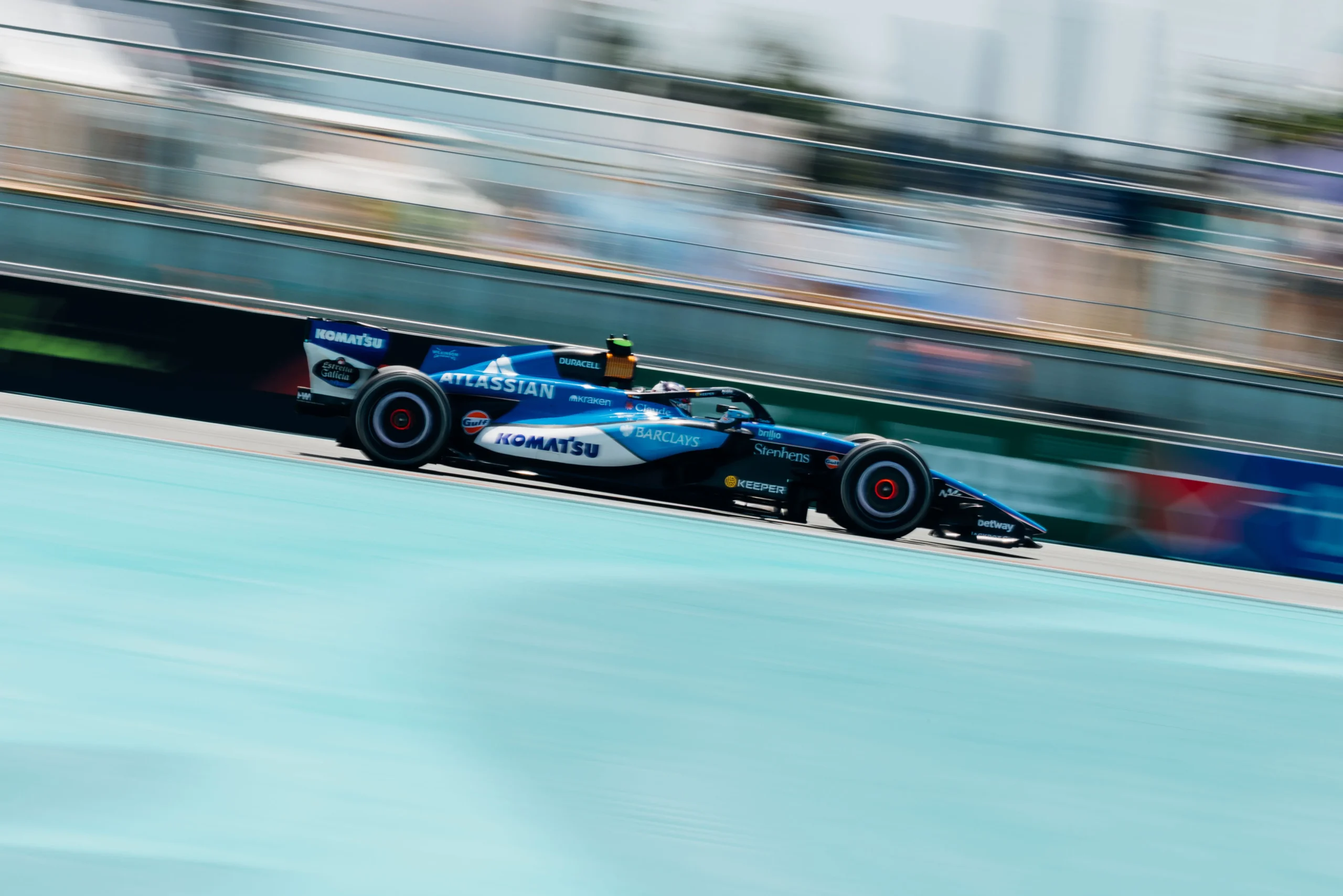 Car Updated Photo Side-profile panning shot of a Williams Formula 1 car racing through the Miami Grand Prix circuit, with the background blurred and turquoise runoff areas emphasizing speed and motion.